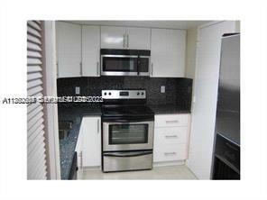 301 Golden Isles Drive, Unit 211 Hallandale Beach, FL 33009 - Photo 3 of 7 a kitchen with a stove and a microwave
