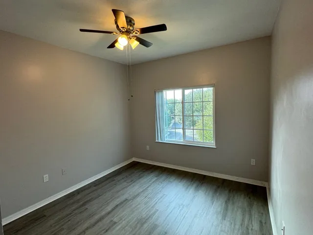 an empty room with a window and a fan
