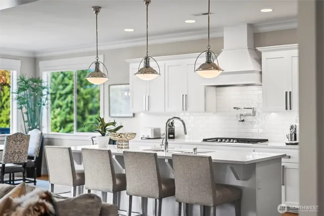 a kitchen with stainless steel appliances granite countertop a sink a stove a refrigerator and white cabinets with wooden floor