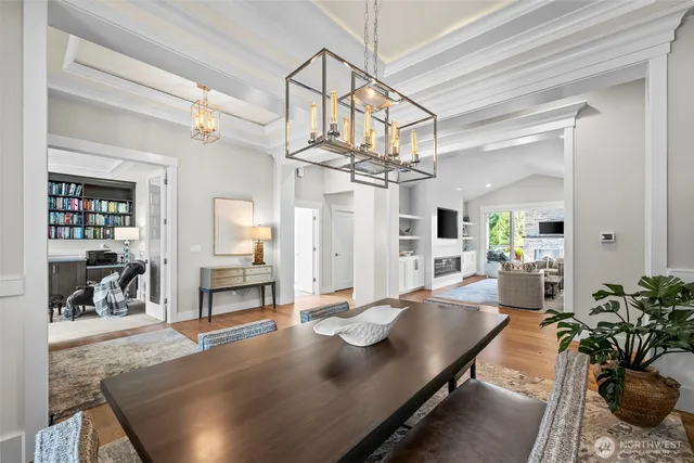 a dining room with wooden floor a chandelier a wooden table and chairs