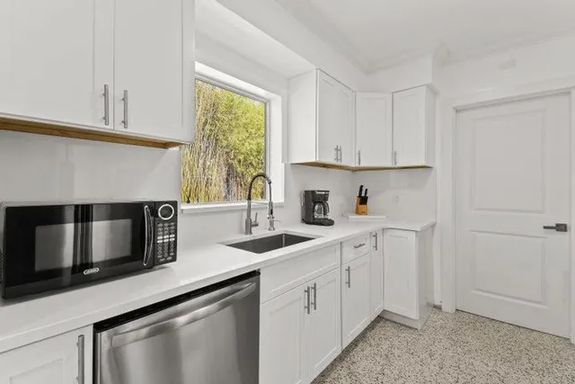 a kitchen with stainless steel appliances granite countertop white cabinets a sink and a oven
