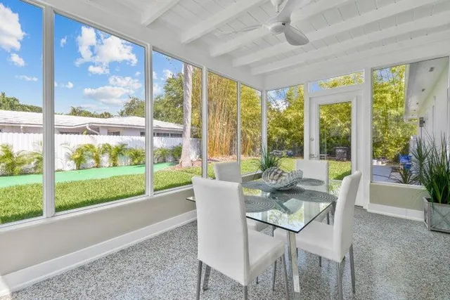 a dining room with wooden floor windows and outdoor space