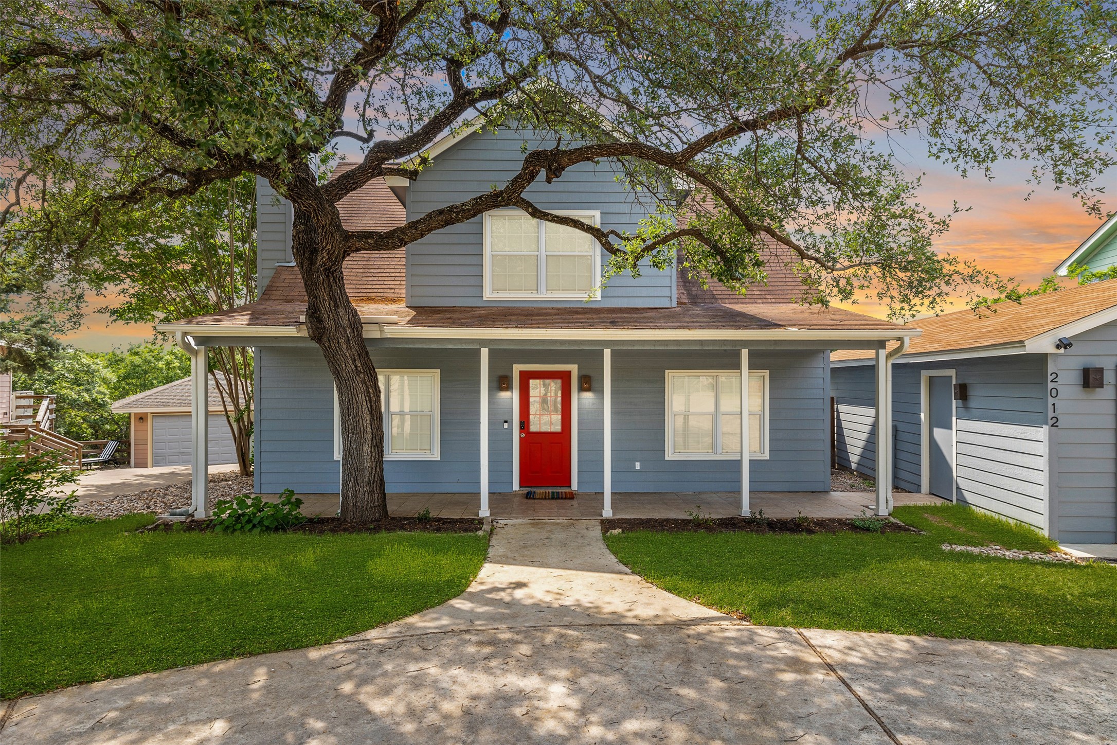 a front view of a house with a garden and trees
