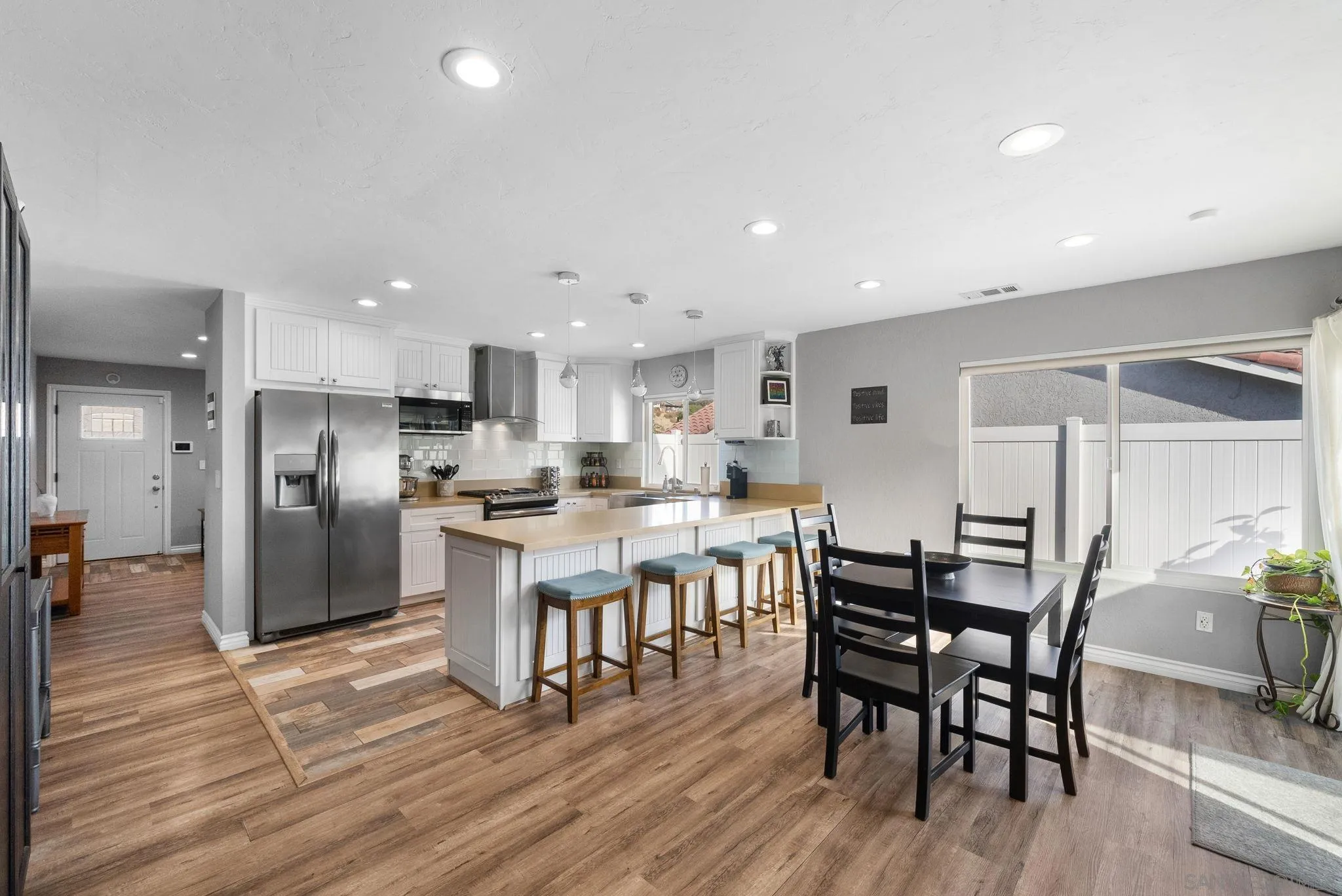 6503 Plaza Ridge Road San Diego, CA 92114 - Photo 12 of 37 a kitchen with stainless steel appliances kitchen island granite countertop a table chairs stove and white cabinets