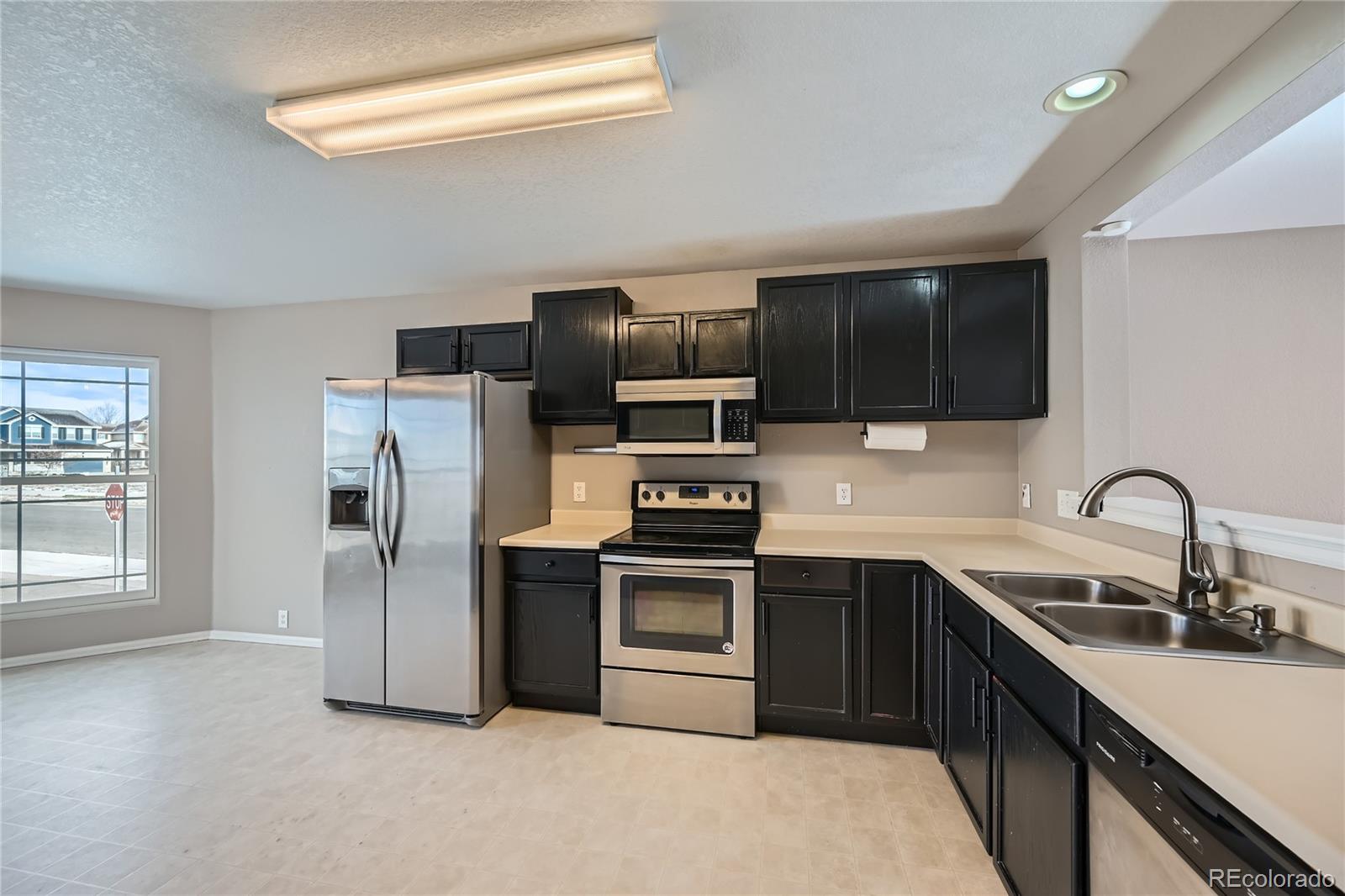 4296 Clover Lane Brighton, CO 80601 - Photo 11 of 35 a kitchen with stainless steel appliances a refrigerator sink and microwave