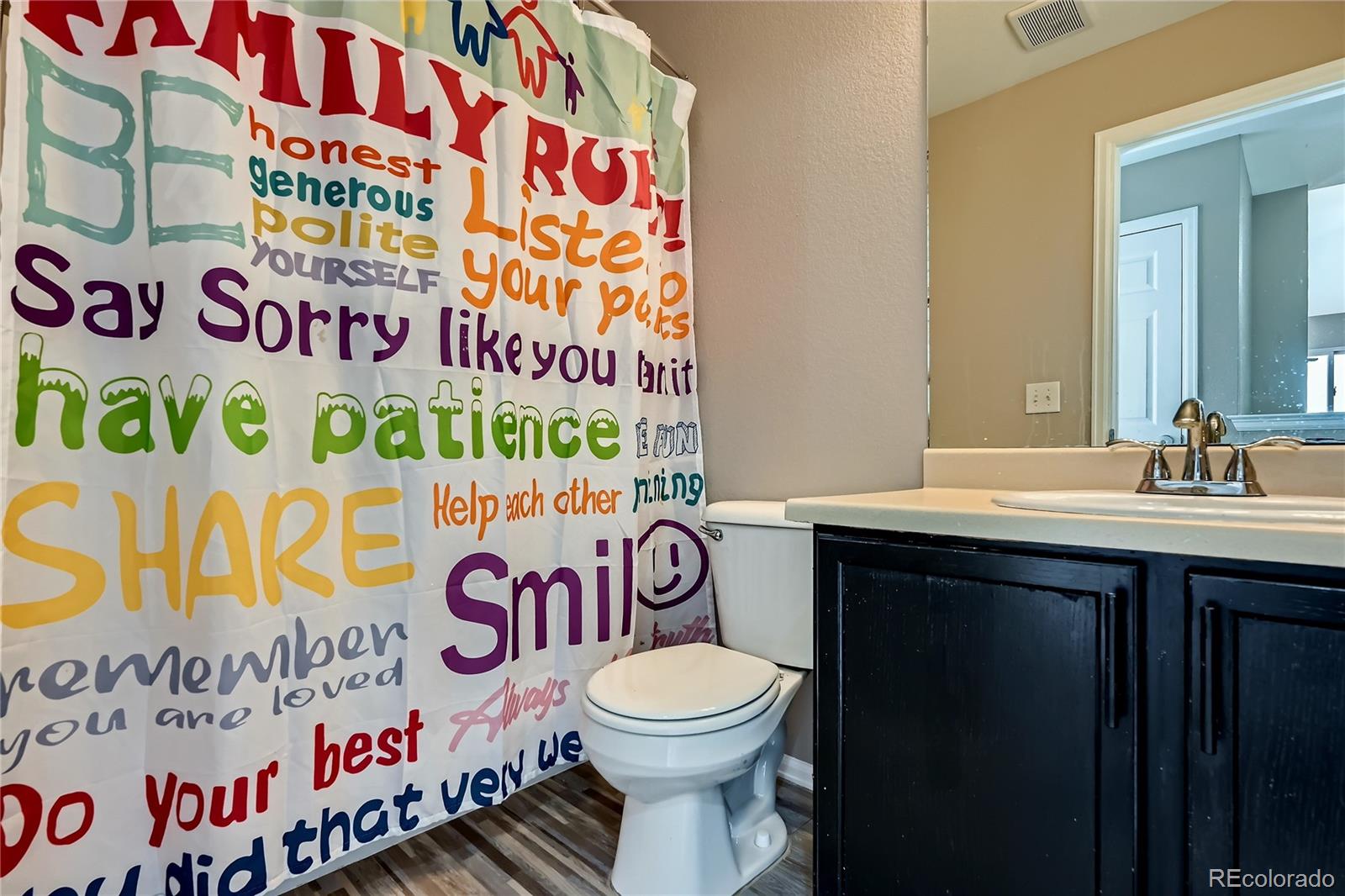 4296 Clover Lane Brighton, CO 80601 - Photo 25 of 35 a bathroom with a sink a toilet and a shower curtain