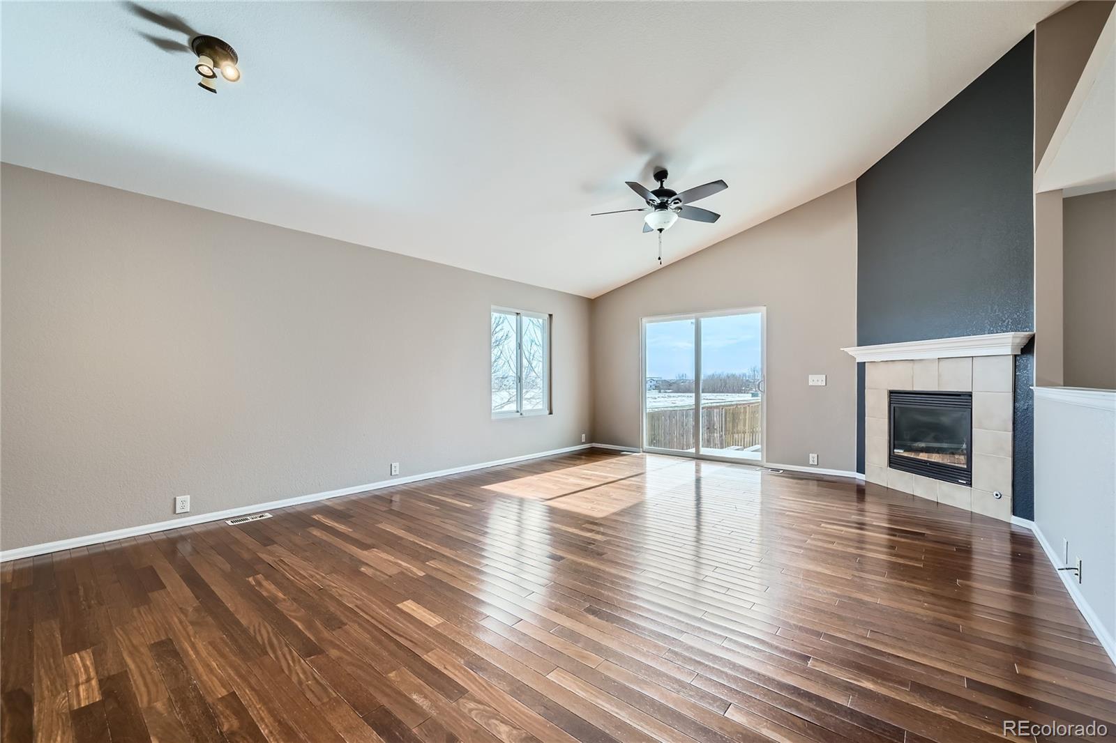4296 Clover Lane Brighton, CO 80601 - Photo 5 of 35 an empty room with wooden floor fireplace and windows