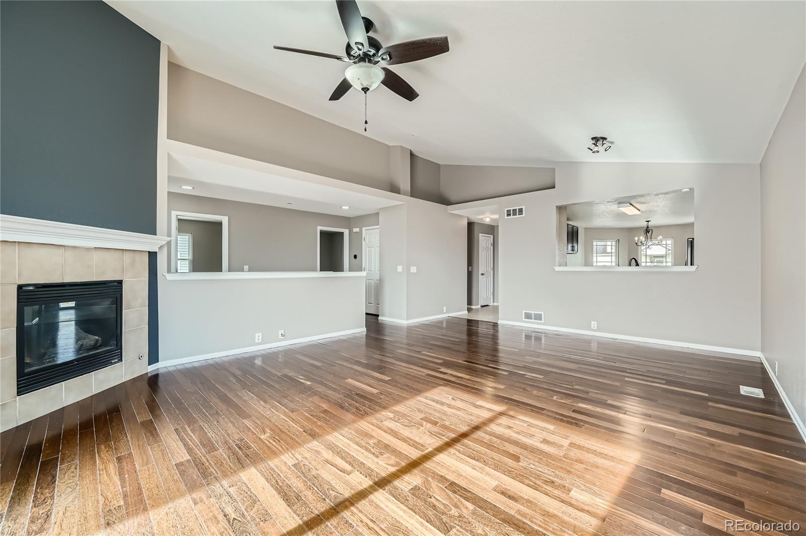 4296 Clover Lane Brighton, CO 80601 - Photo 8 of 35 a view of a livingroom with wooden floor a ceiling fan and windows