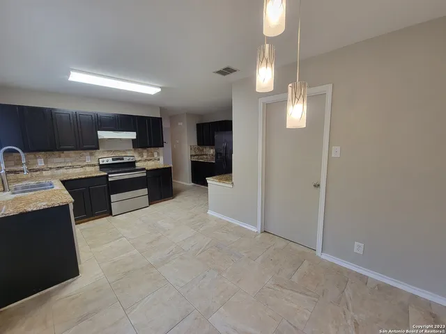 a kitchen with stainless steel appliances granite countertop a sink counter space cabinets and a refrigerator
