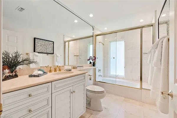 a bathroom with a granite countertop sink mirror vanity and toilet