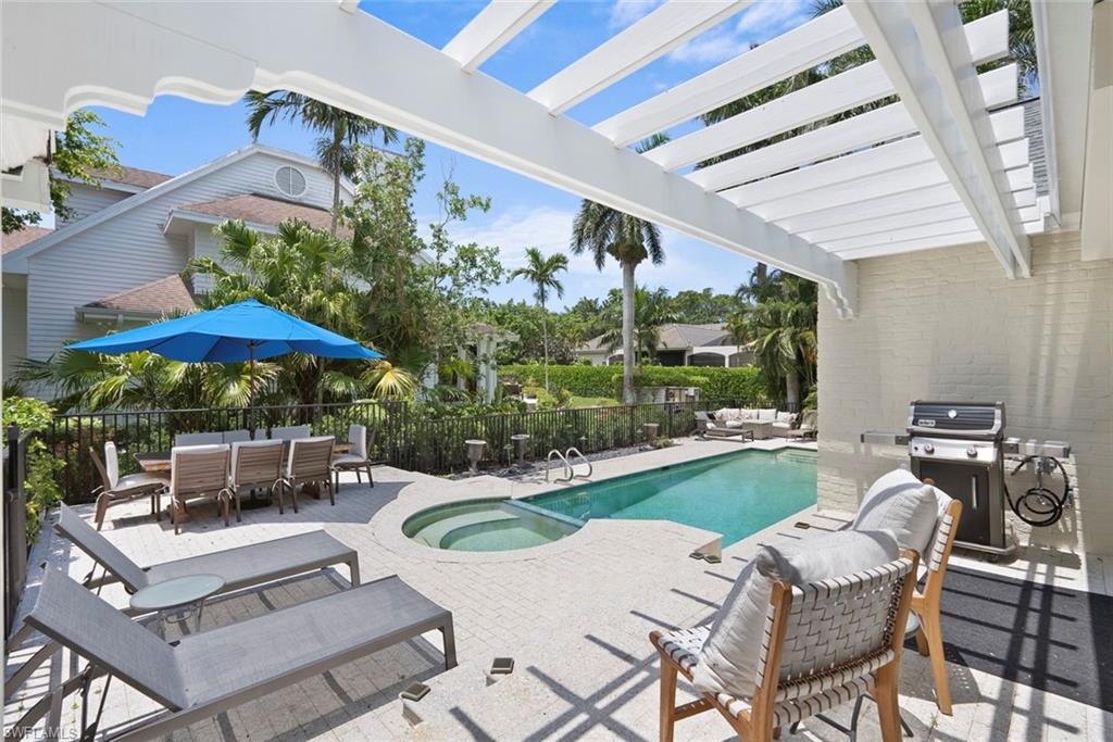 2700 Treasure Lane Naples, FL 34102 - Photo 37 of 44 a view of a patio with couches table and chairs under an umbrella