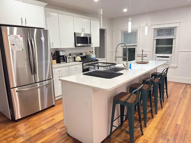 a kitchen with stainless steel appliances a refrigerator a stove a sink a dining table and chairs