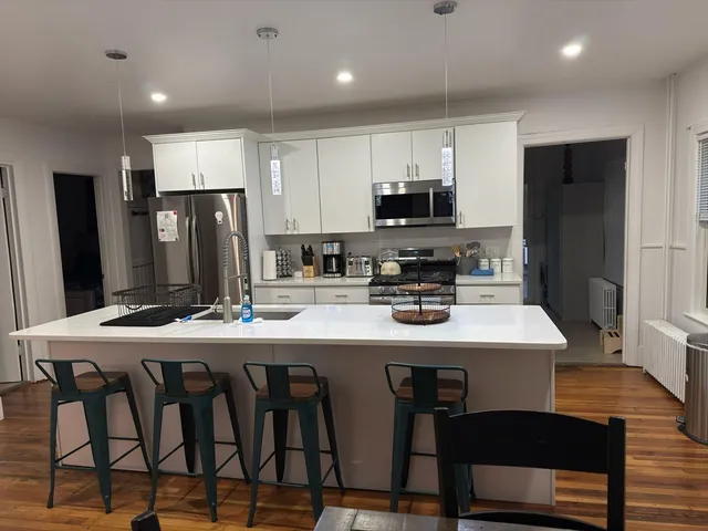 a kitchen with stainless steel appliances a table chairs refrigerator and microwave