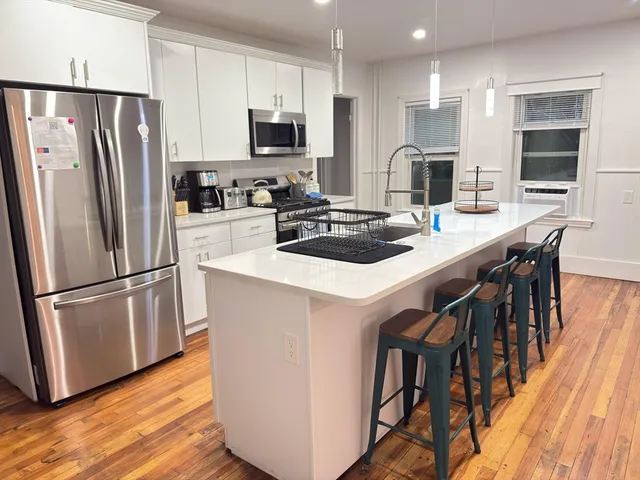 a kitchen with stainless steel appliances a refrigerator a stove a sink a dining table and chairs