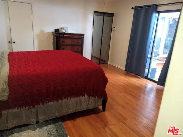 a bedroom with a bed and dresser with wooden floor