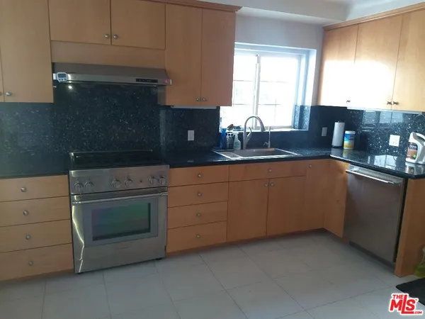 a kitchen with granite countertop cabinets stainless steel appliances a sink and a window