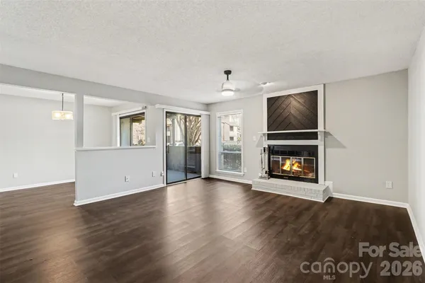 an empty room with wooden floor fireplace and windows