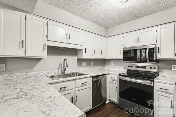 a kitchen with stainless steel appliances granite countertop a stove a sink and a microwave