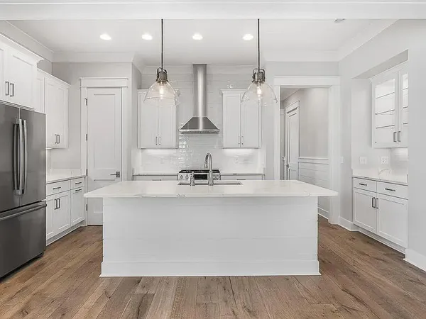 a large kitchen with kitchen island white cabinets and stainless steel appliances
