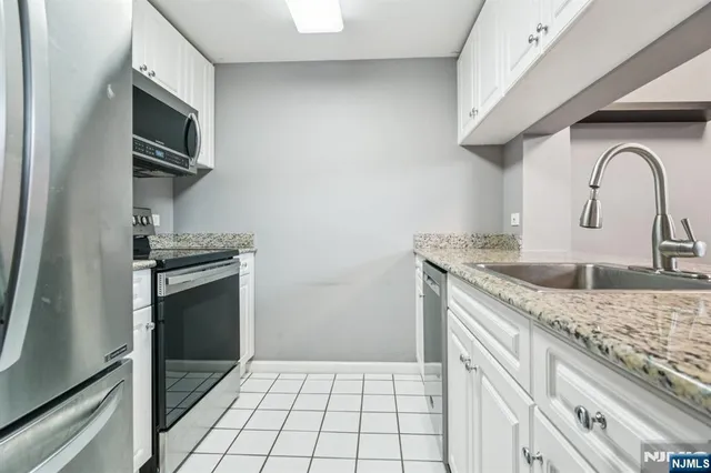 a kitchen with granite countertop a sink stainless steel appliances and cabinets