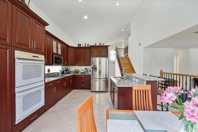 a kitchen with stainless steel appliances granite countertop a refrigerator a stove a sink dishwasher and wooden cabinets with wooden floor