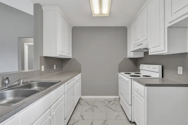 a kitchen with granite countertop a sink stove and cabinets