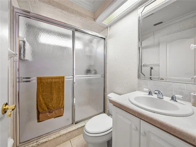 a bedroom with a bed a chandelier and a flat tv screen on dresser