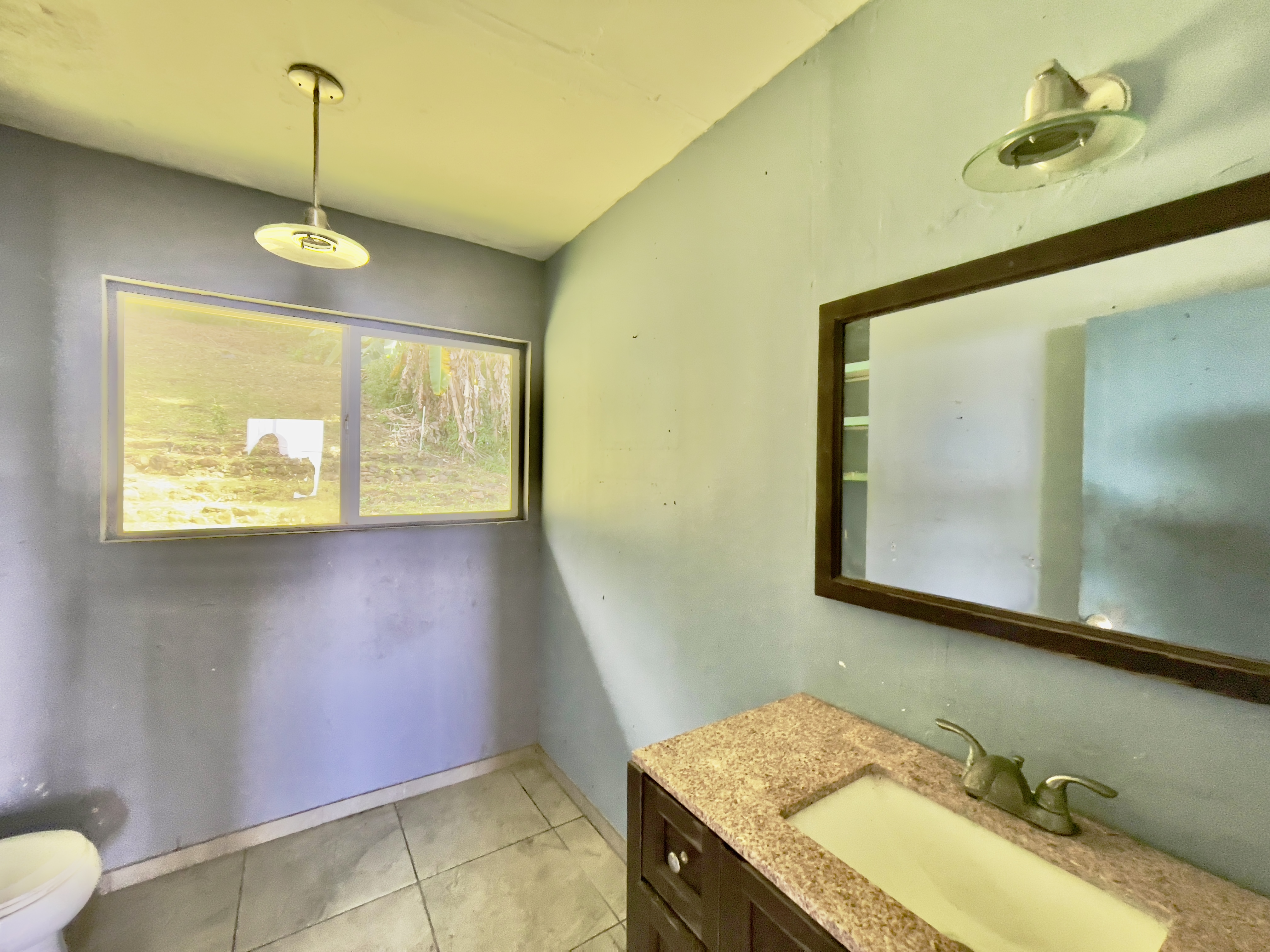 83-5586 Hawaiʻi Belt Road Captain Cook, HI 96704 - Photo 14 of 23 a bathroom with a granite countertop sink and a mirror