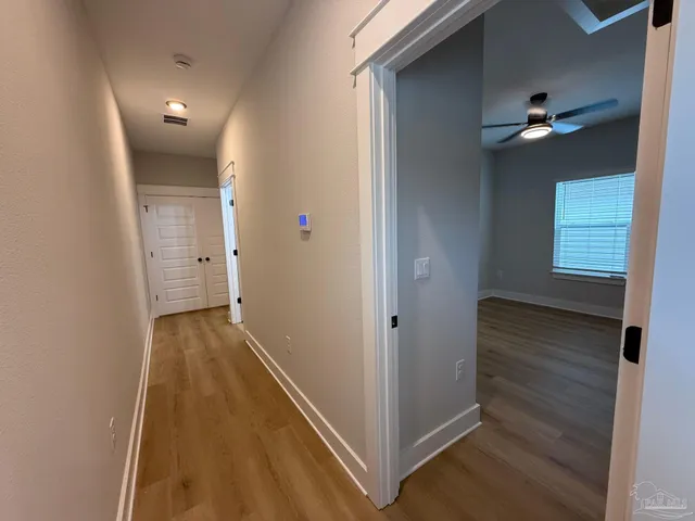 an empty room with wooden floor fan and windows