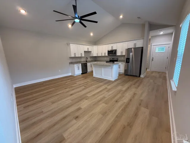 a large kitchen with stainless steel appliances granite countertop a stove a sink dishwasher and a refrigerator with wooden floor