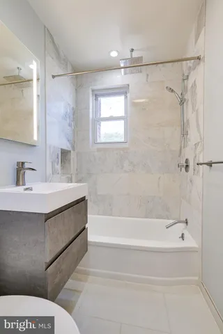 a bathroom with a bathtub shower sink vanity and a toilet