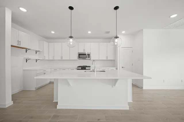 a view of kitchen with stainless steel appliances refrigerator oven stove and wooden floor