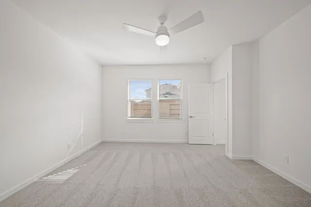 an empty room with windows and ceiling fan