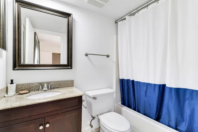 a bathroom with a granite countertop sink toilet and mirror