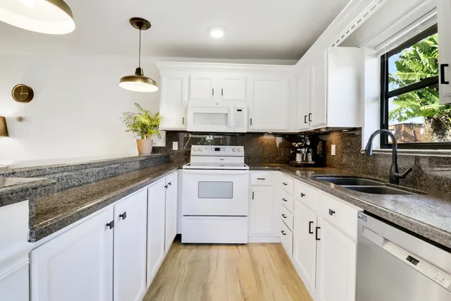 a kitchen with granite countertop white cabinets and white appliances