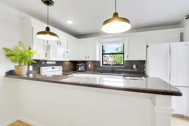 a kitchen with stainless steel appliances granite countertop a sink a stove a dining table and chairs