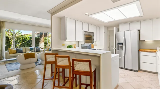 a kitchen with stainless steel appliances granite countertop a table chairs and a refrigerator