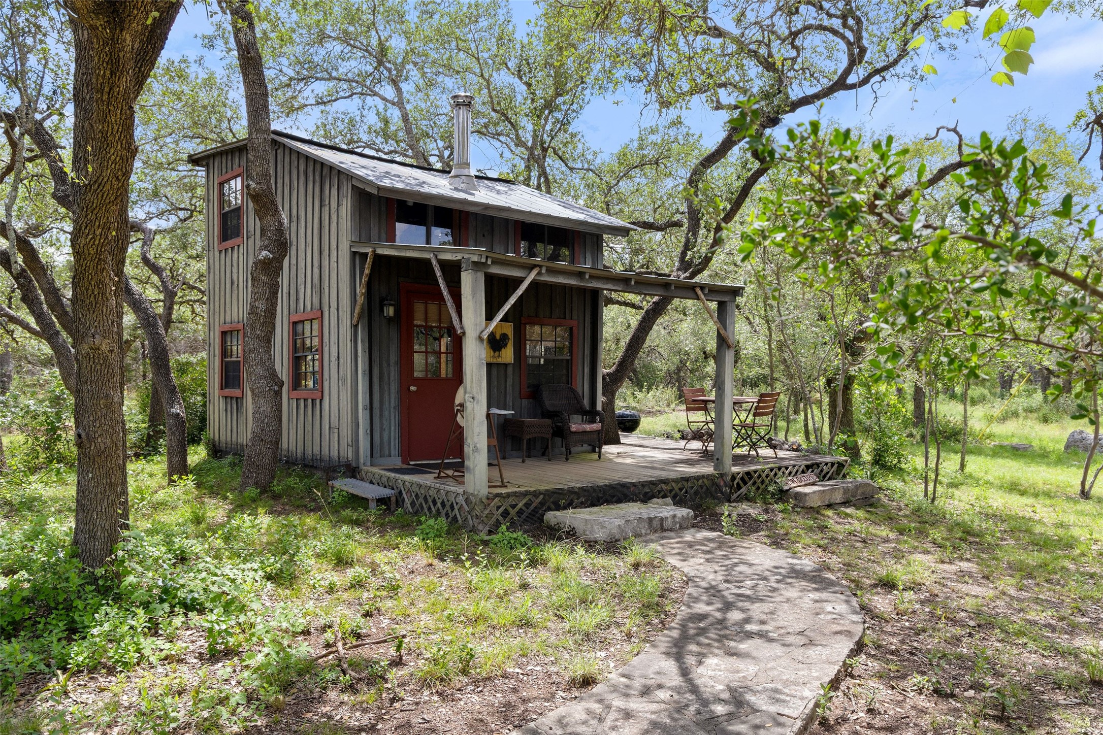 505 Red Corral Ranch Road Wimberley, TX 78676 - Photo 39 of 40 Tucked among mature trees, a rustic cabin offers a welcoming front porch with ample space for outdoor enjoyment.