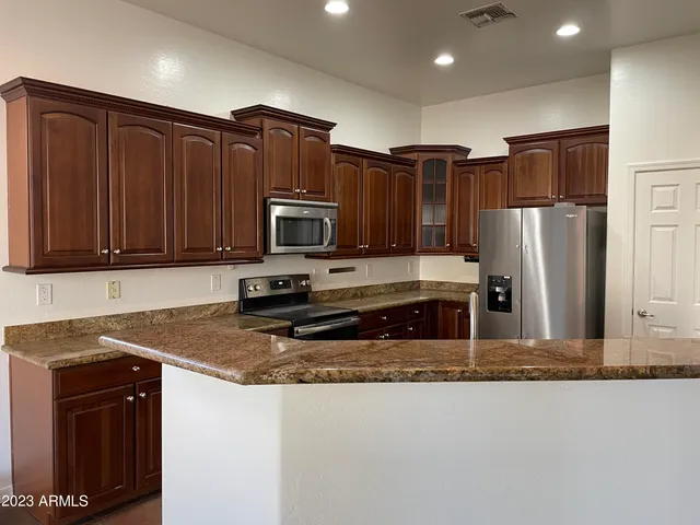 a kitchen with stainless steel appliances granite countertop a refrigerator a stove a sink and a microwave