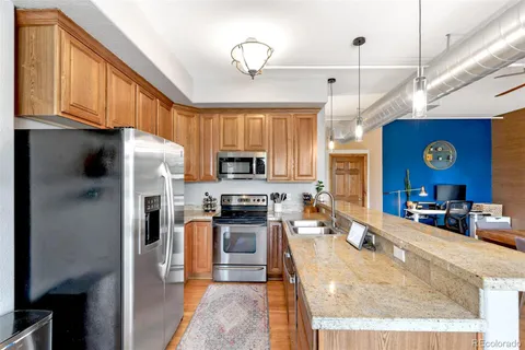 a kitchen with stainless steel appliances granite countertop a refrigerator a stove top oven a sink and dishwasher with wooden floor