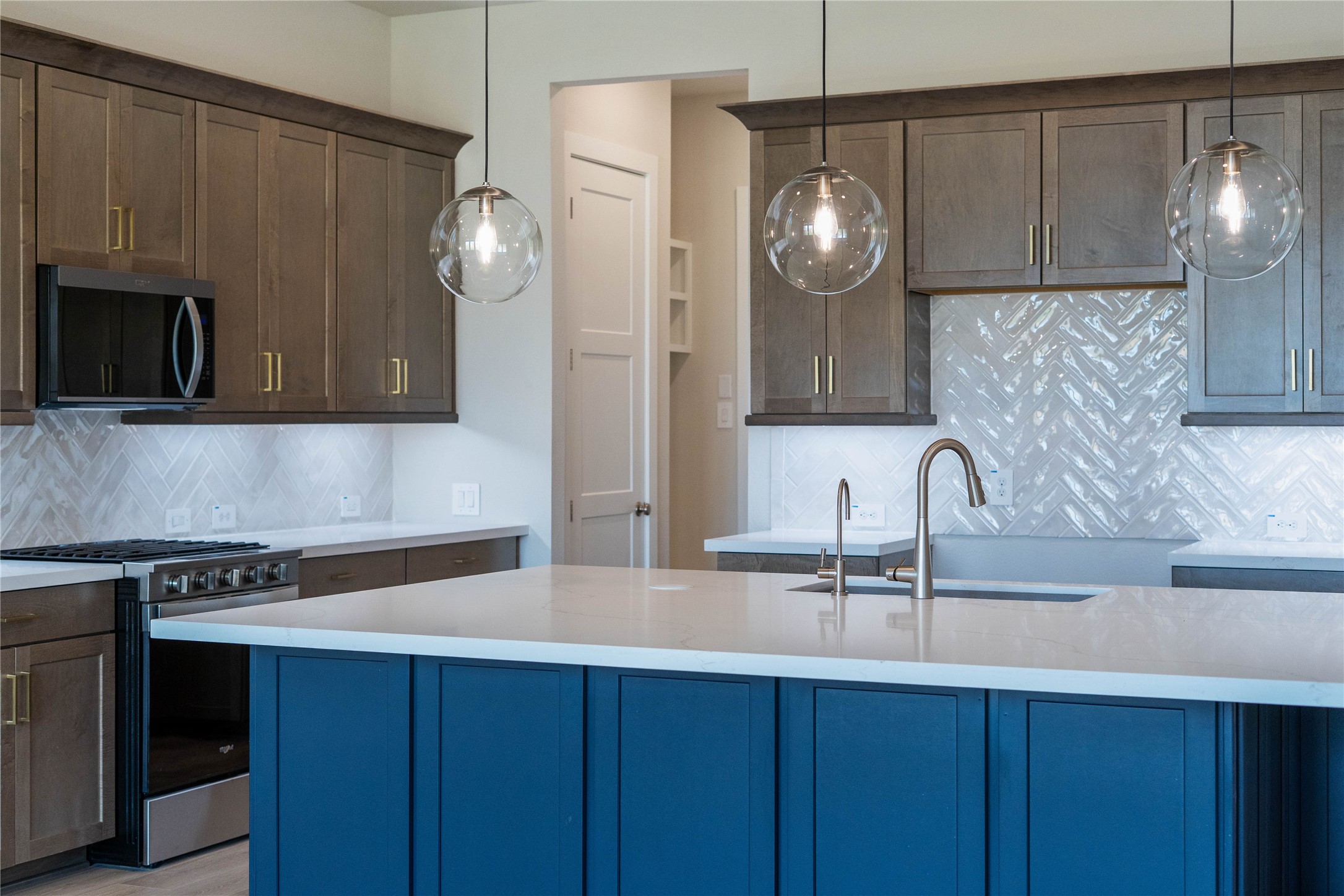 9123 Petroglyph Pt Court Porter, TX 77365 - Photo 18 of 43 The kitchen is more than just a place to cook; it's a central gathering space designed for creating memories, entertaining guests, and daily living. This beautiful kitchen island has an extended breakfast bar and is painted in a gorgeous navy color with quartz countertop, and pendant lighting.