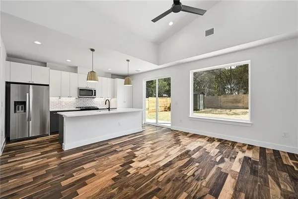 a large kitchen with kitchen island a large window and stainless steel appliances