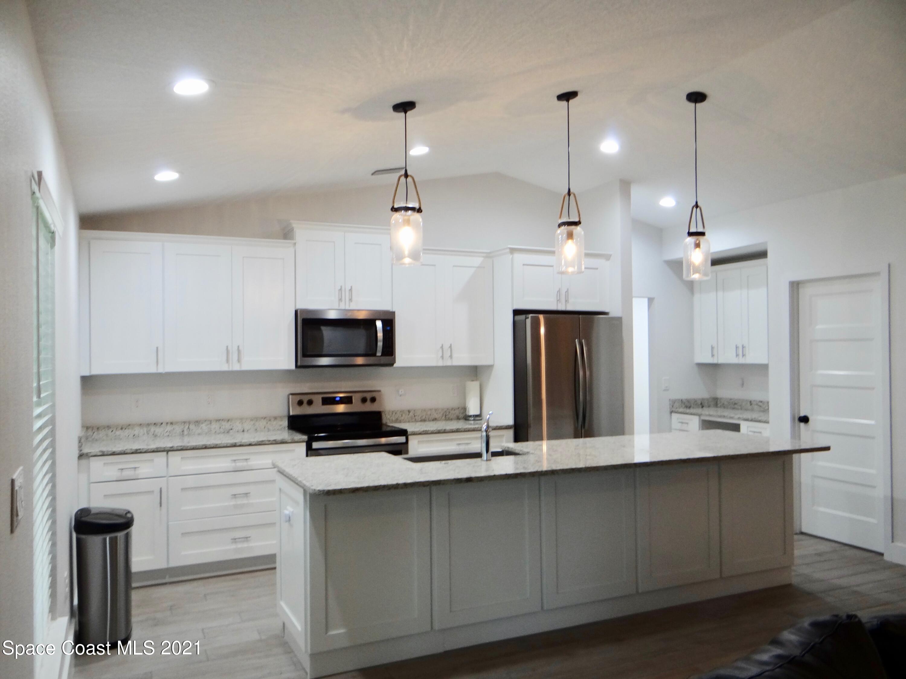 2725 Digby Road Southeast Palm Bay, FL 32909 - Photo 9 of 33 a kitchen with kitchen island white cabinets and stainless steel appliances