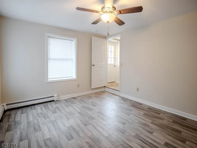 an empty room with wooden floor fan and windows