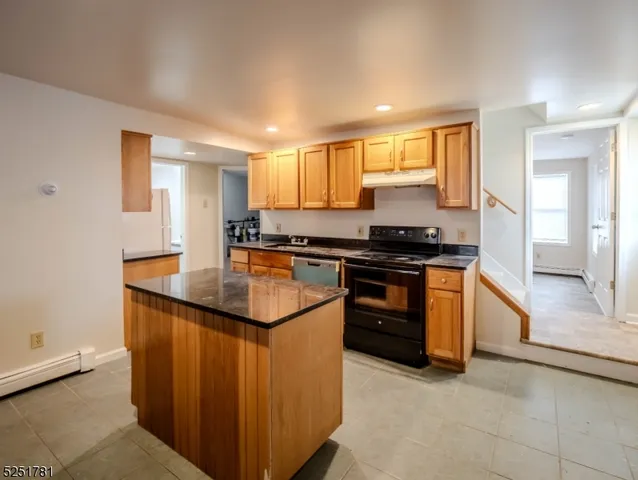 a kitchen with kitchen island granite countertop a sink and a stove