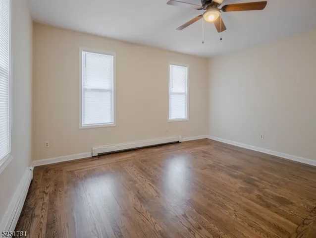 an empty room with wooden floor chandelier fan and windows