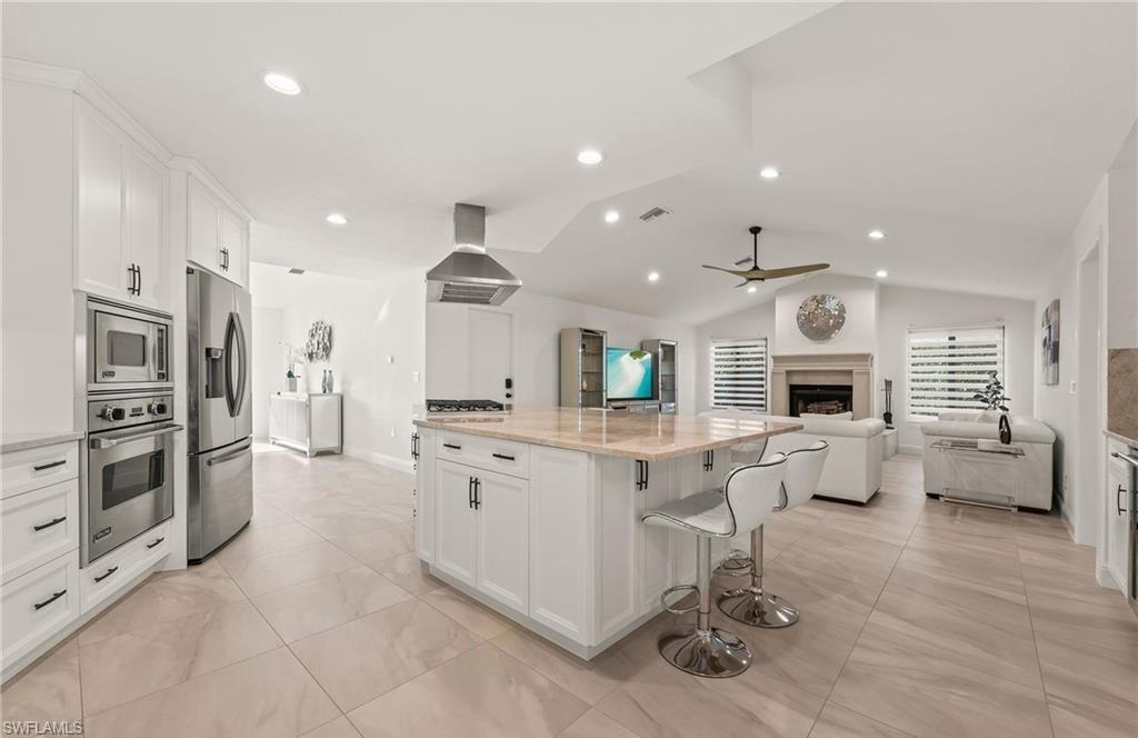 2307 Queens Way Naples, FL 34112 - Photo 9 of 41 a large white kitchen with stainless steel appliances kitchen island granite countertop a large counter top and stainless steel appliances