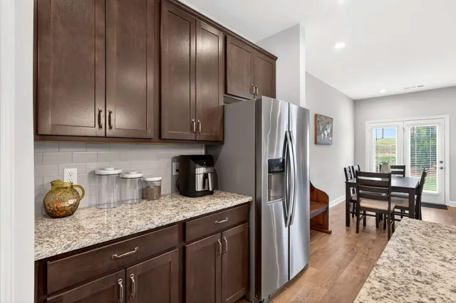 a kitchen with granite countertop kitchen island stainless steel appliances a refrigerator a sink a stove and cabinets