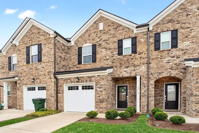 a view of a brick house with yard and plants