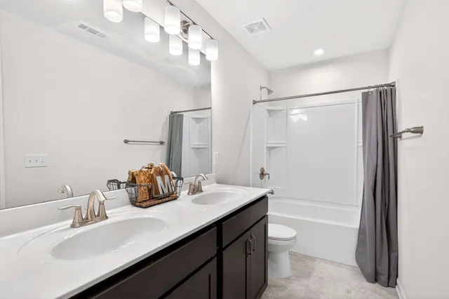 a bathroom with a double vanity sink toilet mirror and bathtub